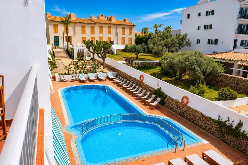 Piscina y jardín del Hotel S'Algaret con las dos plantas de habitaciones